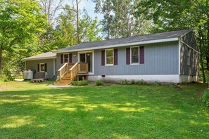 A single-story house with a front porch, a small deck, and a well-maintained lawn. - Charming 3-bedroom house with AC and WiFi on Sandy Pond. (Sandy Creek)
