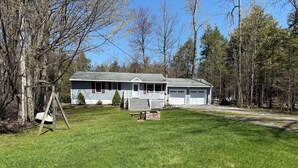 A single-story house with a front porch, a garage, and a lawn. - Charming 3-bedroom house with AC and WiFi on Sandy Pond. (Sandy Creek)
