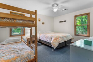 A room with bunk beds, a desk, a chair, a ceiling fan, and a window with blinds.