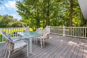 A deck with a glass-top table and chairs, surrounded by a white railing. - Charming 3-bedroom house with AC and WiFi on Sandy Pond. (Sandy Creek)