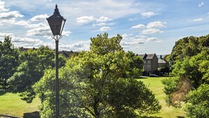 A street lamp, lush greenery, and a building with multiple windows. - The Cottage on the Green - UK47990 (Chipping Norton)