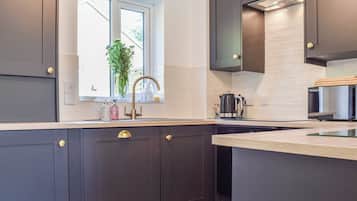 A modern kitchen with dark cabinetry, a window with a view, a coffee maker, and a microwave.