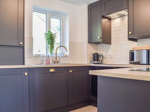 A modern kitchen with dark cabinetry, a window with a view, a coffee maker, and a microwave.