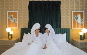 A hotel room with a bed, two nightstands, and two wall-mounted lamps.