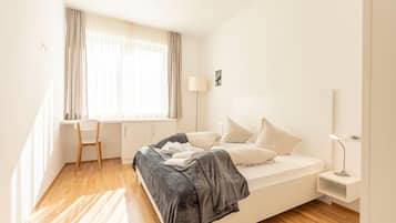 Un dormitorio moderno con una cama, un escritorio y una silla.