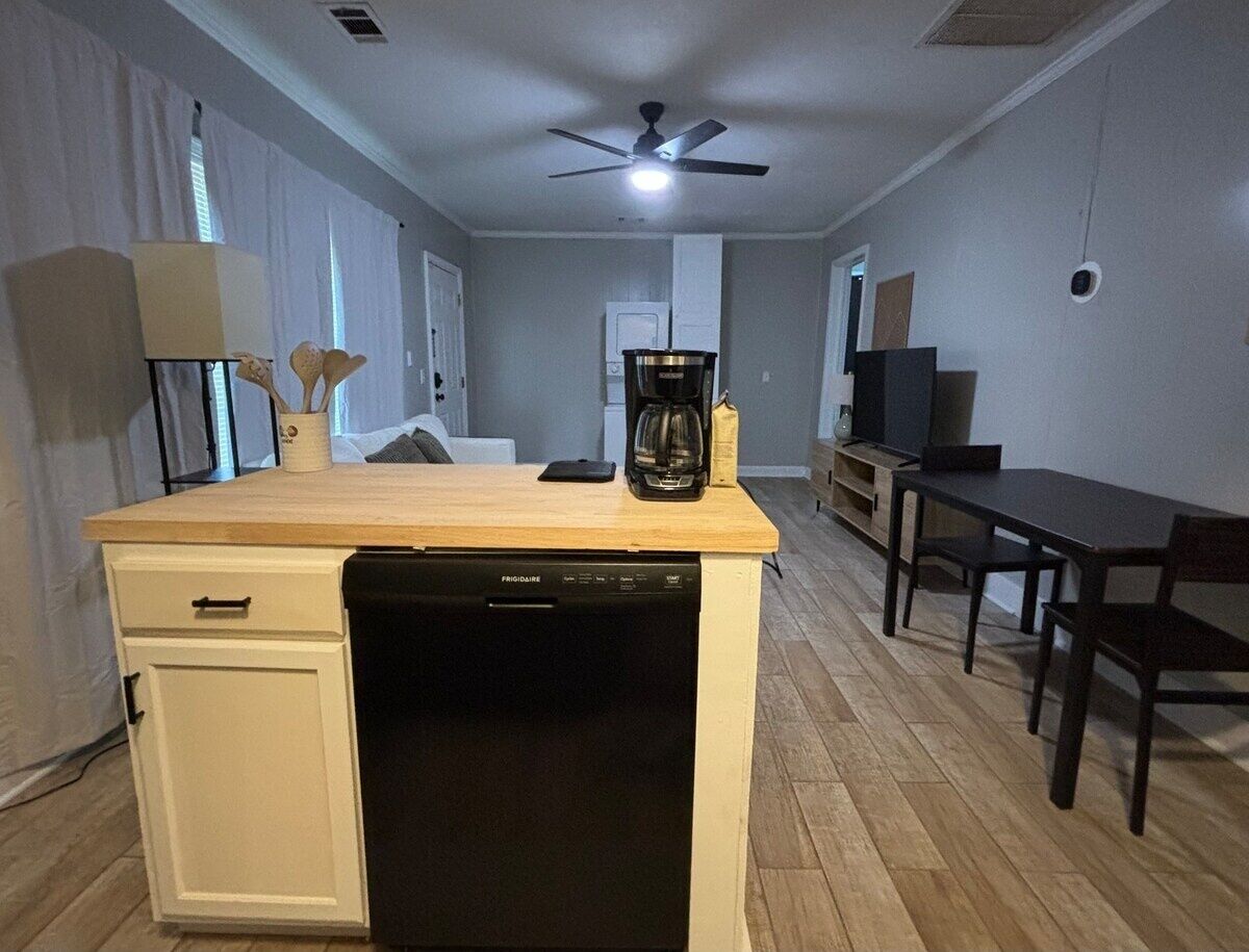 Una cocina compacta con lavavajillas, cafetera y comedor con mesa y sillas.