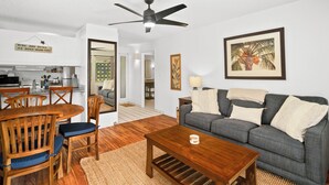 Uma sala de estar com sofá cinza, mesa de centro de madeira e um espaço de refeições com mesa e cadeiras de madeira.