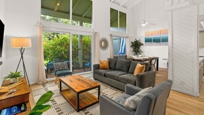 A spacious living room with a large sofa, a coffee table, and a dining area with a table and chairs. - Summer Deal Princeville Townhouse Near Anini Beach with Pool (Princeville)