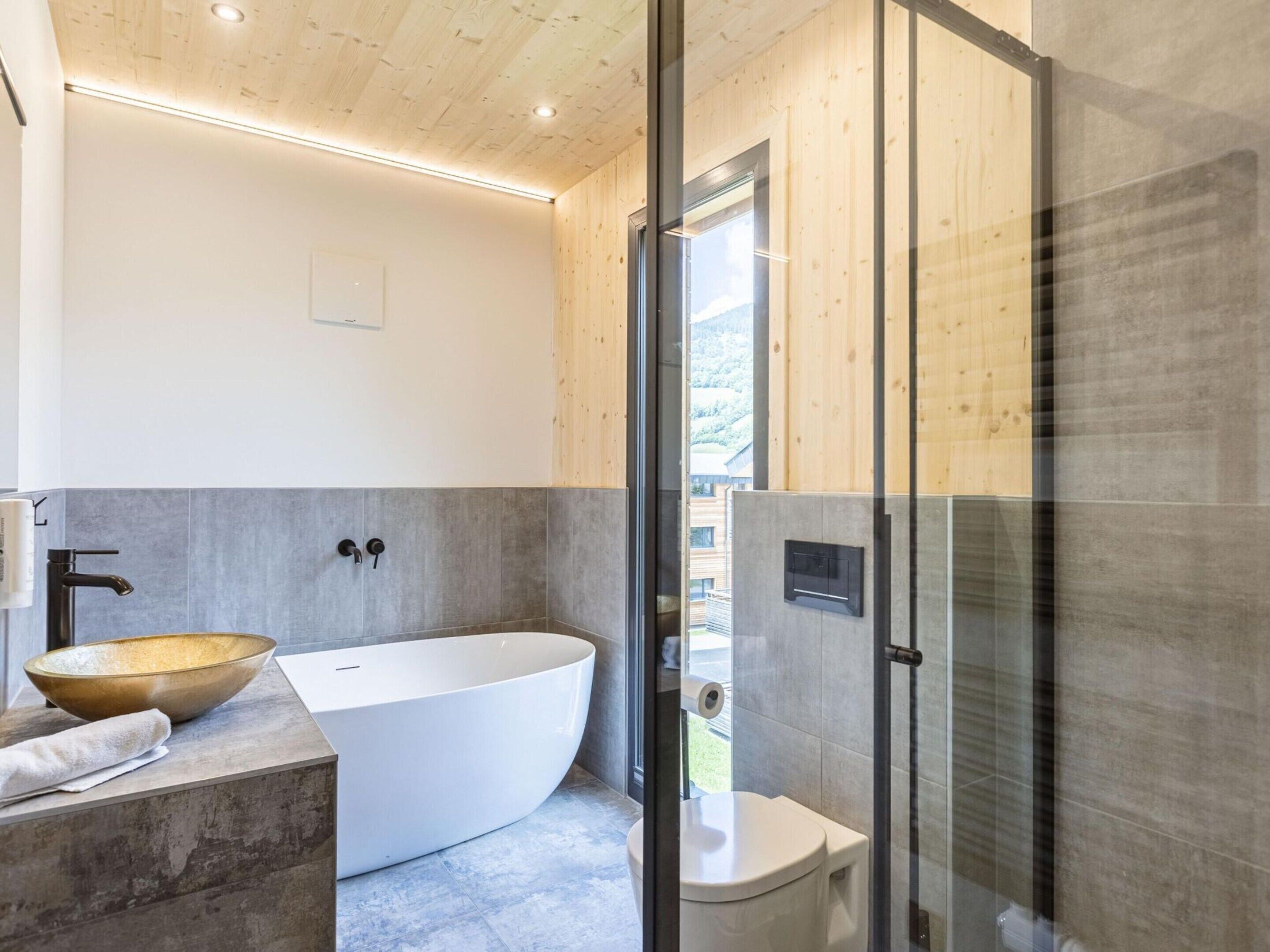 A modern bathroom with a freestanding bathtub, a toilet, and a glass-enclosed shower area.