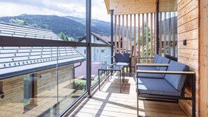 A balcony with a glass railing, wooden deck, and a seating area with a table and chairs. - Penthouse With Sauna (Sankt Georgen am Kreischberg)