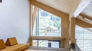 A modern interior with a large window, wooden beams, a sofa, and a rug. - Penthouse With Sauna (Sankt Georgen am Kreischberg)