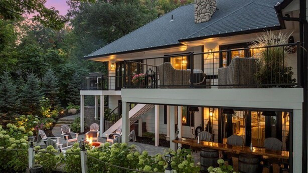 Een tweelaags huis met een overdekte patio, buiten zitplaatsen en een stenen schoorsteen.