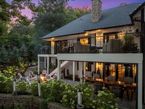 Een tweelaags huis met een overdekte patio, buiten zitplaatsen en een stenen schoorsteen.