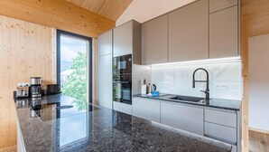 A modern kitchen with a granite countertop, stainless steel appliances, and a large window offering a view of greenery. - Attractive Penthouse With Sauna (Sankt Georgen am Kreischberg)