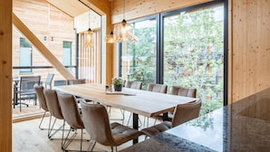 A modern dining area with a large wooden table, multiple chairs, and hanging pendant lights. - Attractive Penthouse With Sauna (Sankt Georgen am Kreischberg)