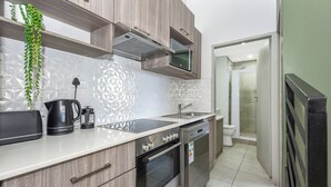 A modern kitchen with wooden cabinets, a built-in microwave, a kettle, and a dishwasher.