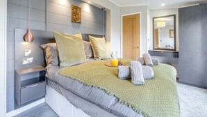 A modern bedroom with a bed, bedside tables, a mirror, and a hanging light fixture. - 2 bedroom accommodation in Roadford Lake, near Launceston (Roadford Lake, near Launceston)