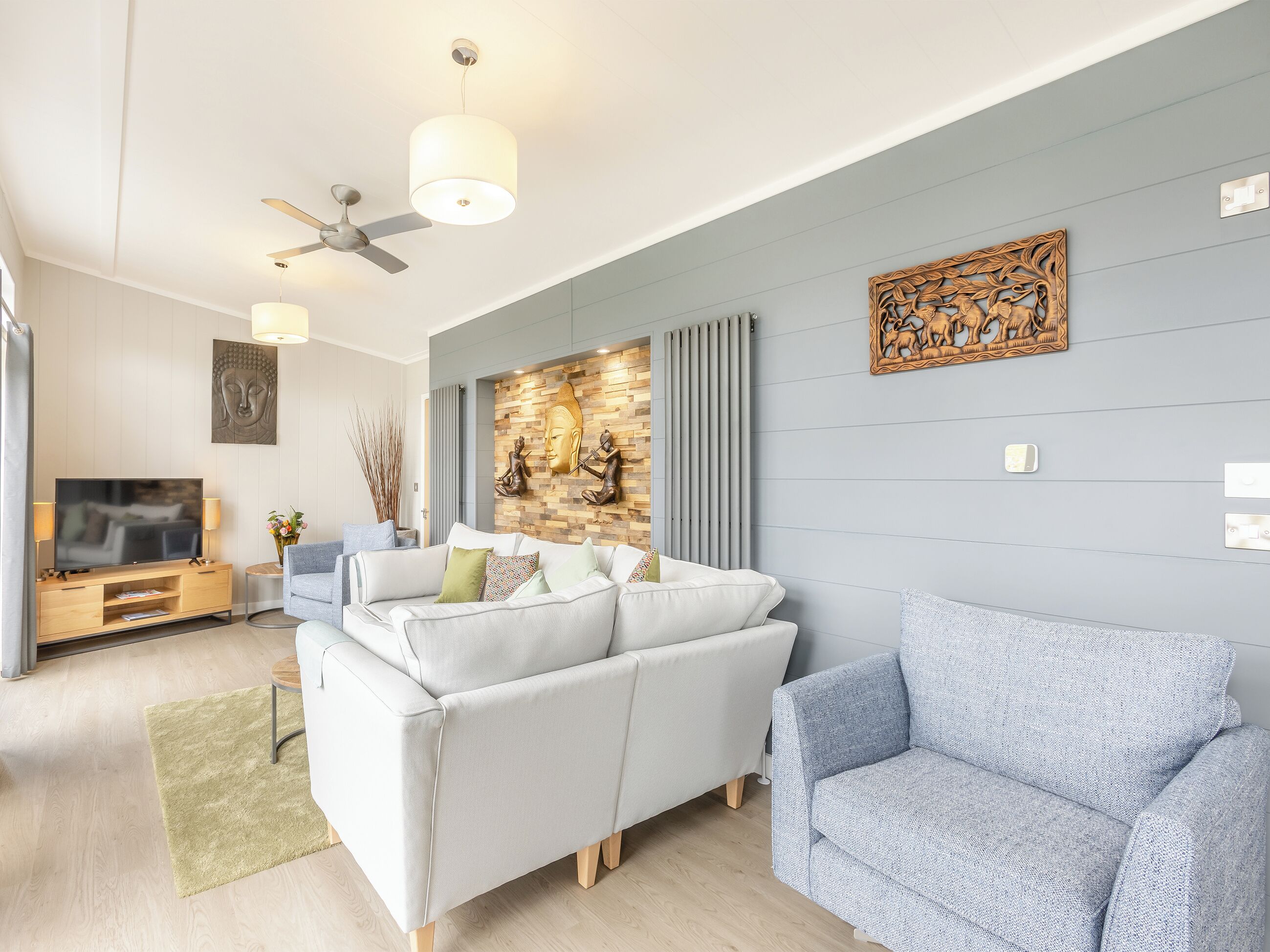 A modern living room with a sofa, a television, and a ceiling fan.