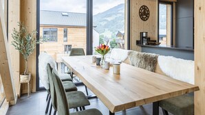 A wooden dining area with a long table, chairs, and a view of a mountain landscape through large windows. - Amazing Penthouse With Sauna (Sankt Georgen am Kreischberg)