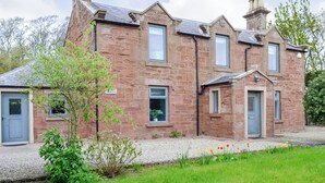 A stone building with multiple windows and doors, surrounded by greenery and a gravel path. - 3 bedroom accommodation in Arbroath (Arbroath)