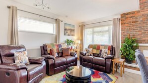 A modern living room with leather sofas, a coffee table, and a colorful rug.