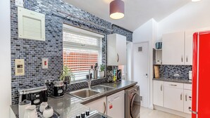 A modern kitchen with a black and white tiled backsplash, stainless steel appliances, and a red refrigerator.
