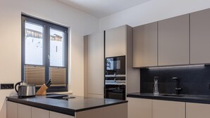 A modern kitchen with a central island, built-in appliances, and a window with blinds. - Nice Apartment With Shared Pool (Sankt Martin am Tennengebirge)