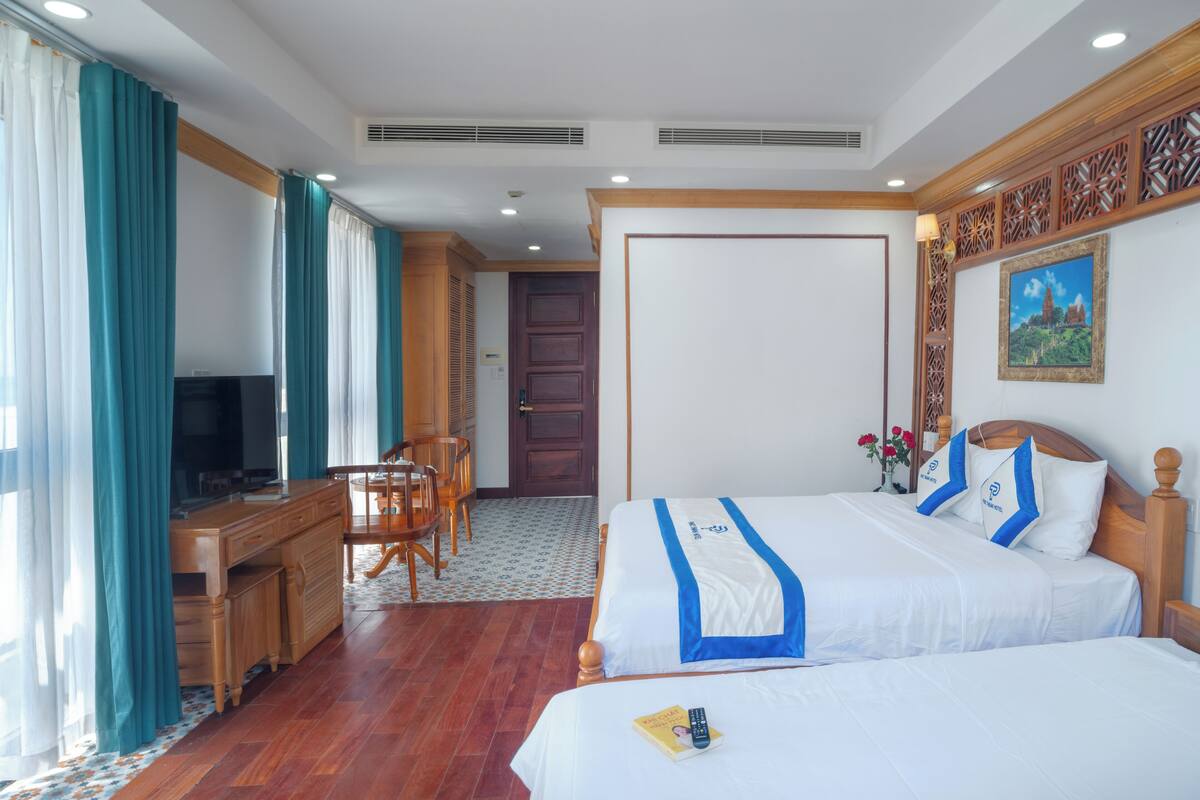 Une chambre d’hôtel avec deux lits, un bureau, une télévision et un coin repas.