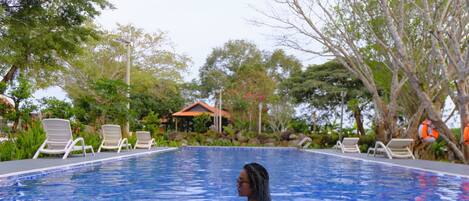 A swimming pool with lounge chairs and a pavilion in the background.