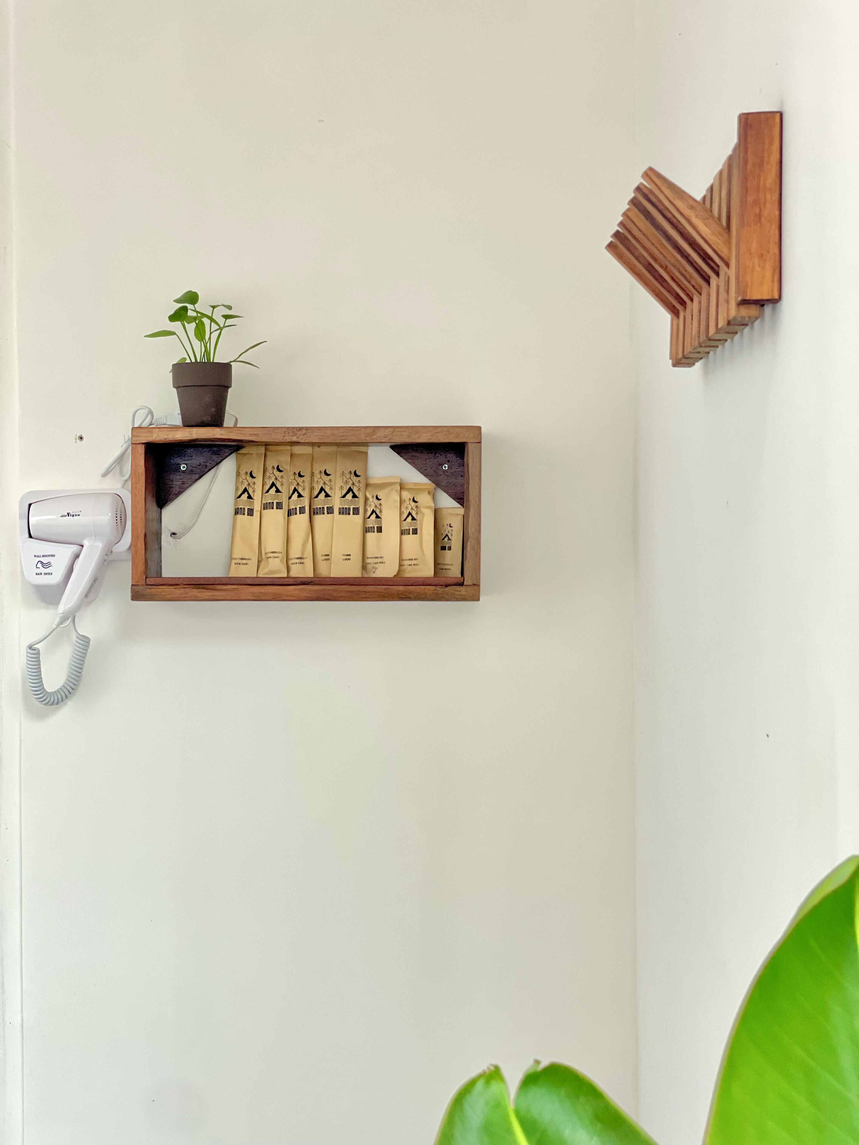 Una repisa de madera con una planta en maceta y un juego de artículos de aseo.