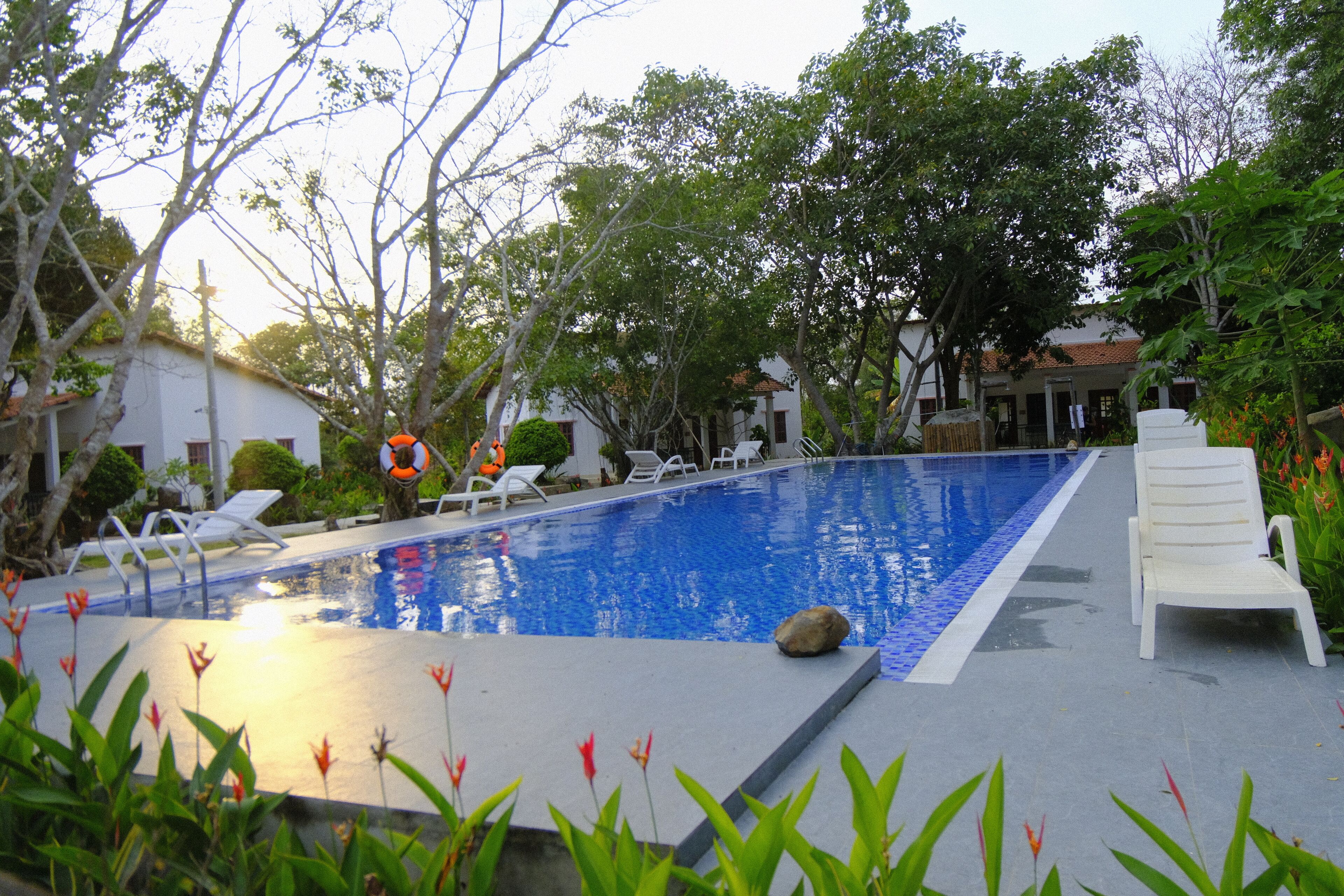 Una piscina con sillones de descanso y un flotador.