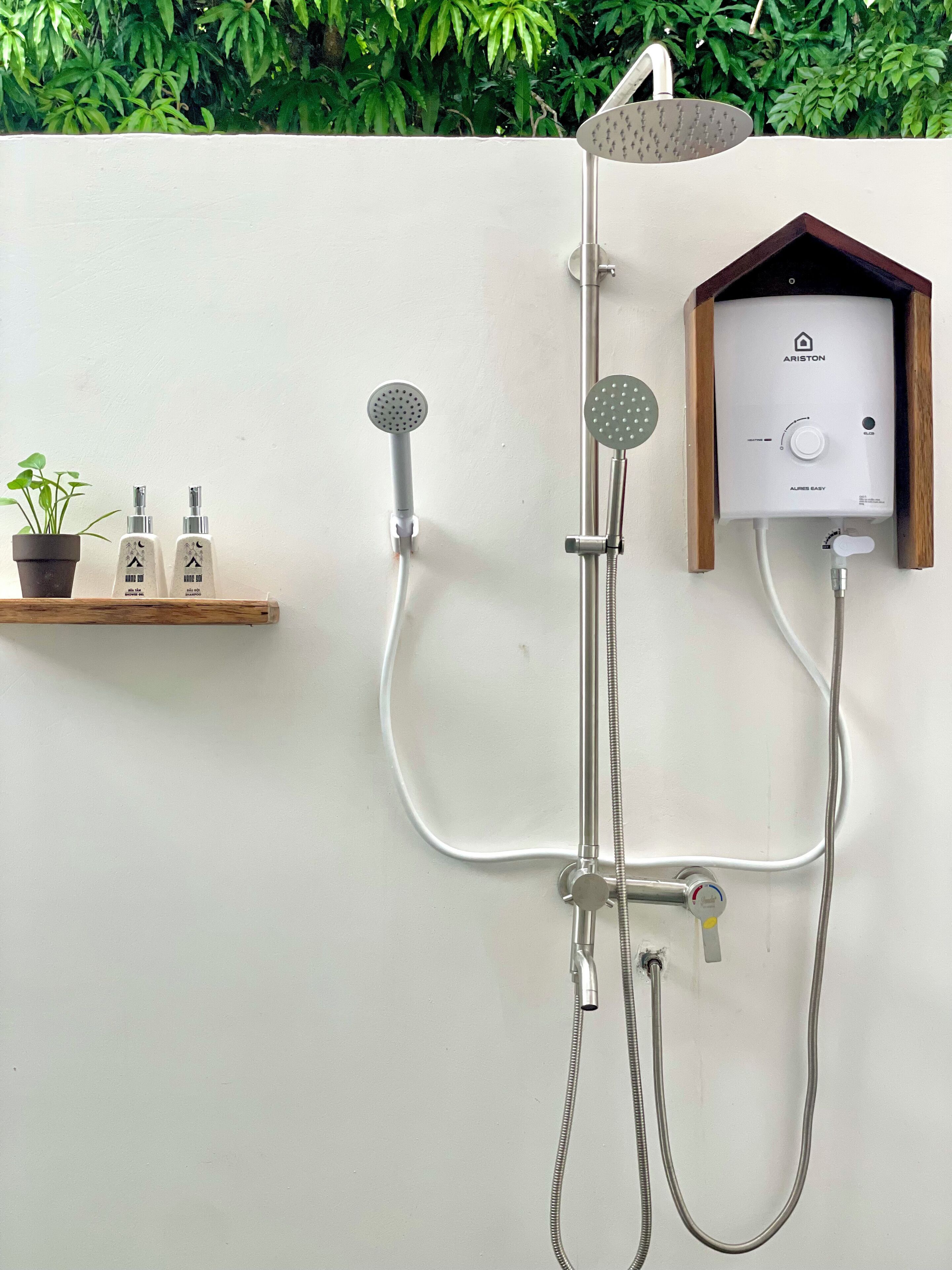 A wall-mounted shower system with a control panel, two showerheads, and a handheld shower attachment.