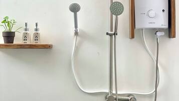 A wall-mounted shower system with a control panel, two showerheads, and a handheld shower attachment.