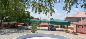 A courtyard with a fountain, covered seating areas, and a building with a red roof. - The Great Turk Reef Hotel (Lodwar)