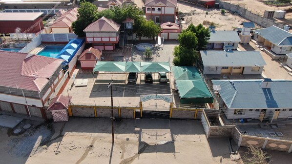 An aerial view of a hotel complex with multiple buildings, a swimming pool, and a fenced parking area. - The Great Turk Reef Hotel (Lodwar)