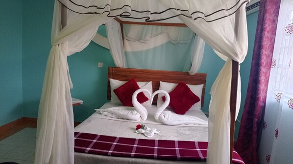 A bed with a canopy, red pillows, and a red and white checkered blanket.