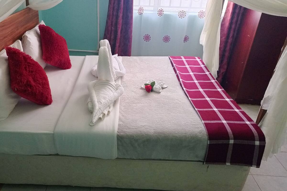 A bed with a white mattress, red pillows, and a white blanket.