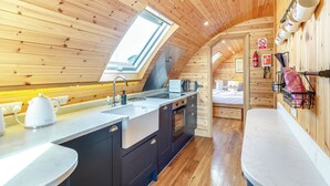L’intérieur chaleureux d’un chalet comprend une cuisine équipée d’un évier, d’une cuisinière et d’un plafond en bois.