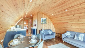 Un intérieur chaleureux en bois, avec un coin repas, un canapé et une cuisine.