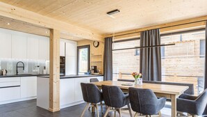 A modern kitchen with white cabinets, a black countertop, and a wooden ceiling. - Attractive Holiday Home With Pool (Sankt Georgen am Kreischberg)
