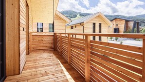 A wooden balcony with a view of other wooden buildings and a mountainous landscape. - Attractive Holiday Home With Pool (Sankt Georgen am Kreischberg)