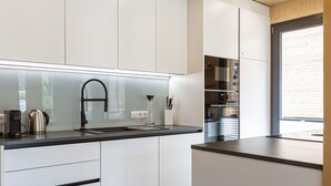 A modern kitchen with white cabinets, a black countertop, and stainless steel appliances. - Attractive Holiday Home With Pool (Sankt Georgen am Kreischberg)