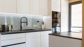 A modern kitchen with white cabinets, a black countertop, and stainless steel appliances.