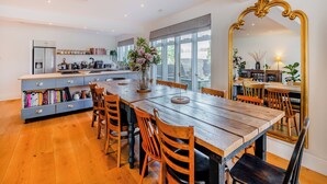 A spacious kitchen with a dining area, large windows, and a mirror with an ornate frame.