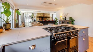 A modern kitchen with a large island, a stone fireplace, and a dining area with a view.