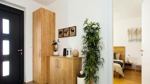 Une chambre à coucher moderne avec une tête de lit en bois, une table de chevet avec une lampe et une grande plante en pot.
