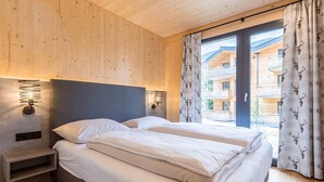 A wooden-paneled bedroom with a bed, nightstands, and a view of a building through a window. - Spacious Apartment With Pool (Sankt Georgen am Kreischberg)