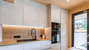 A modern kitchen with a wooden countertop, a black faucet, and built-in appliances including an oven and a dishwasher. - Spacious Apartment With Pool (Sankt Georgen am Kreischberg)