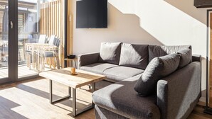 Una sala de estar moderna con un sofá, una mesa de centro y un televisor montado en la pared.