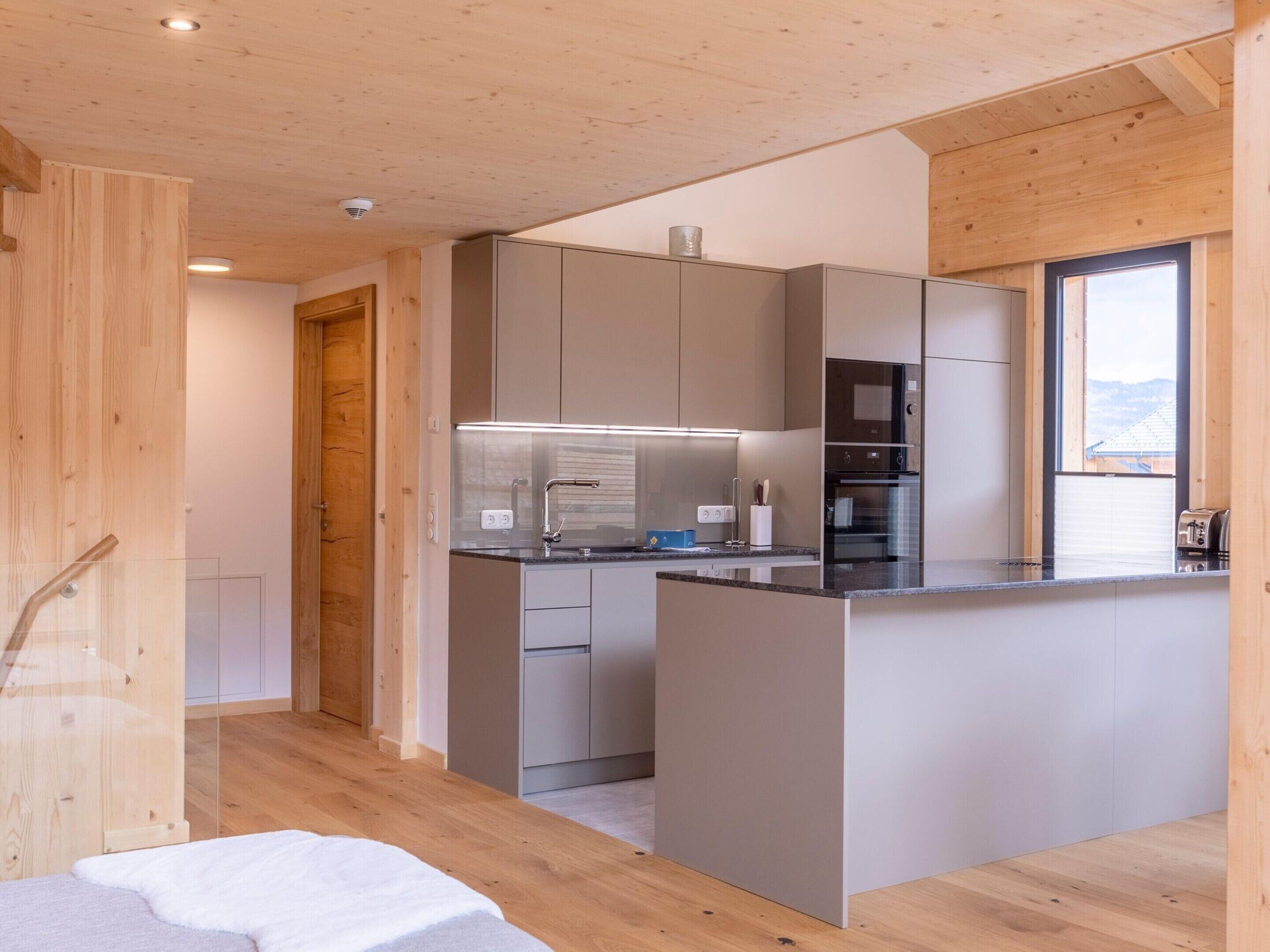 A modern kitchen with wooden walls, a central island, and built-in appliances.